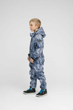 Child wearing a blue Softshell Onesie for Kids, featuring a hood and elastic cuffs, perfect for outdoor activities.