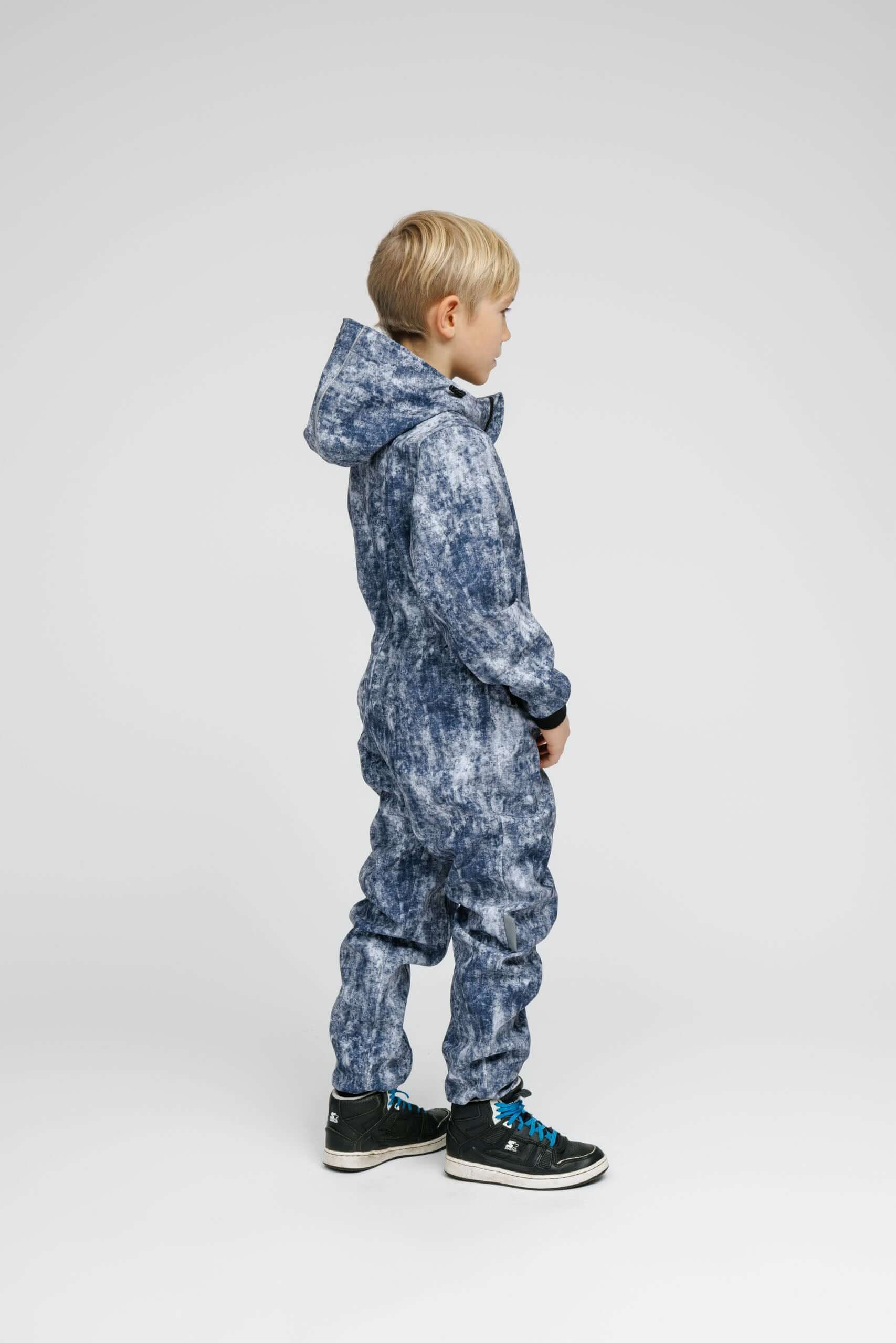 Child wearing a Softshell Onesie for Kids in a stylish design with a hood, showcasing its weather-resistant features.