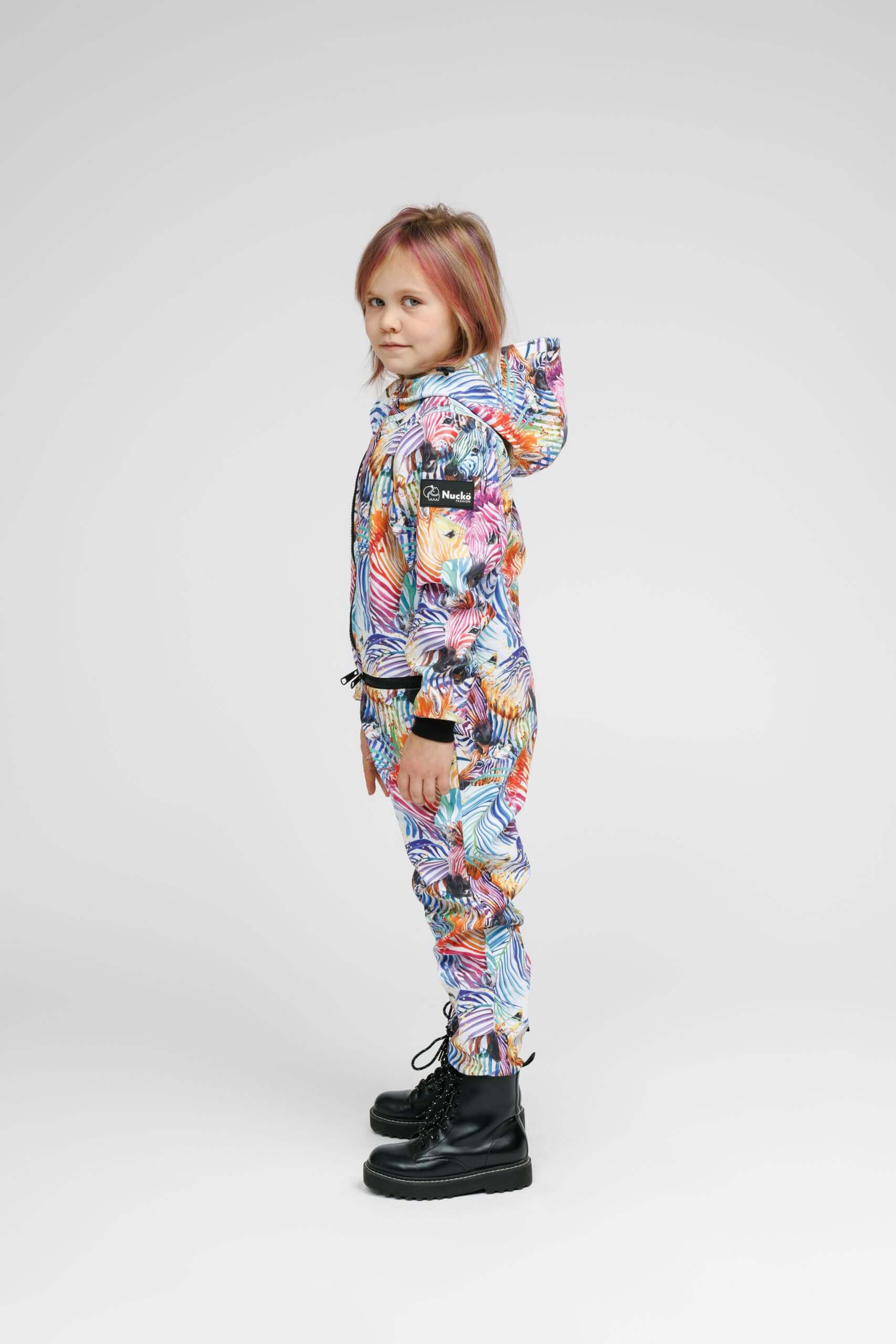 Colorful side view of a child wearing a weather-resistant kids onesie with a hood and zippered pockets.