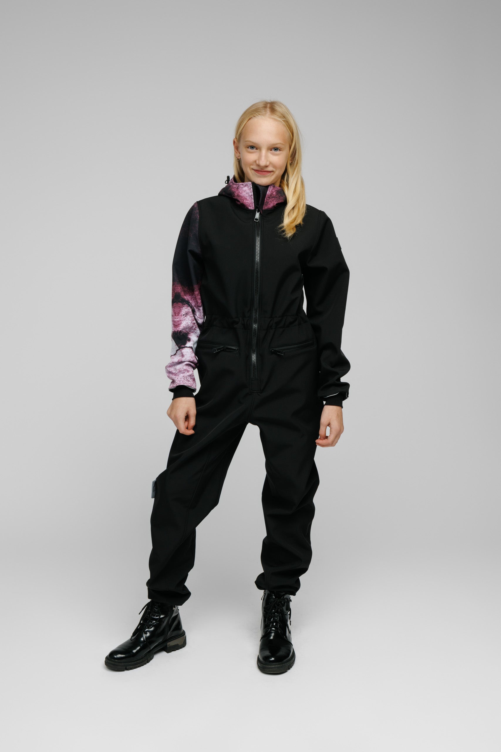 Softshell Onesie for Kids worn by a child, featuring a stylish design with adjustable elements and zippered pockets.