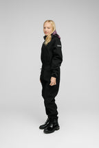 Child wearing a Softshell Onesie for Kids in black with a purple hood, showcasing adjustable features and a snug fit.