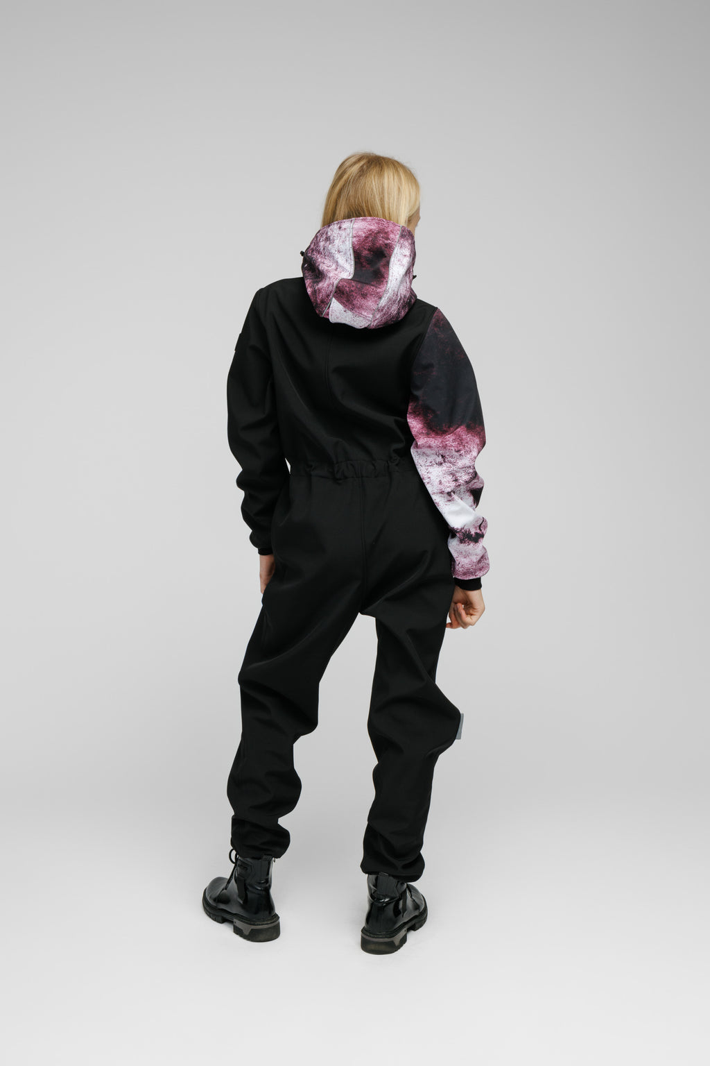 Softshell Onesie for Kids shown from the back, featuring a black design with colorful hood and sleeves.