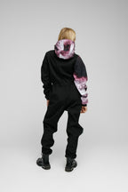 Softshell Onesie for Kids shown from the back, featuring a black design with colorful hood and sleeves.