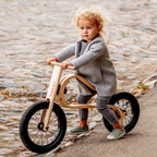 Leg&go Balance Bike 3in1 with a child riding on a cobblestone path, showcasing innovative wooden design.
