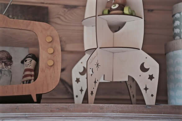Rocket shelf space decor made of wood with charming star cut-outs, perfect for children's rooms and space enthusiasts.