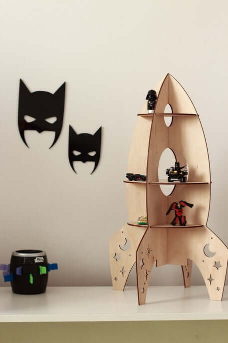 Rocket shelf space decor featuring a wooden rocket-shaped shelf with toys and batman-themed wall decorations.