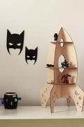 Rocket shelf space decor featuring a wooden rocket-shaped shelf with toys and batman-themed wall decorations.