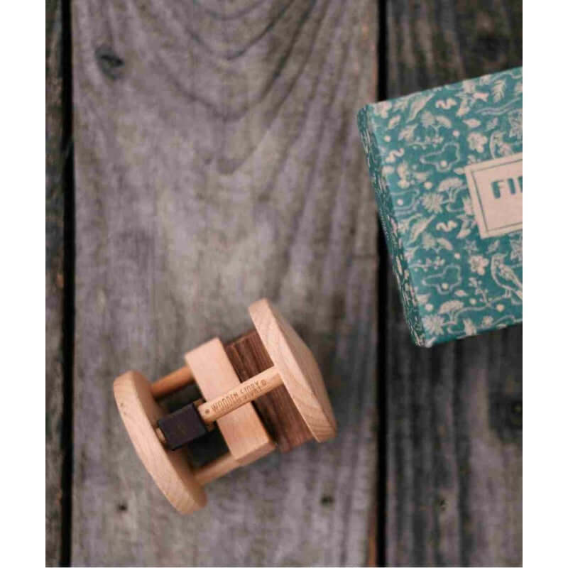 Fieldfare wooden rattle for fine motor skills on wood background with decorative box.