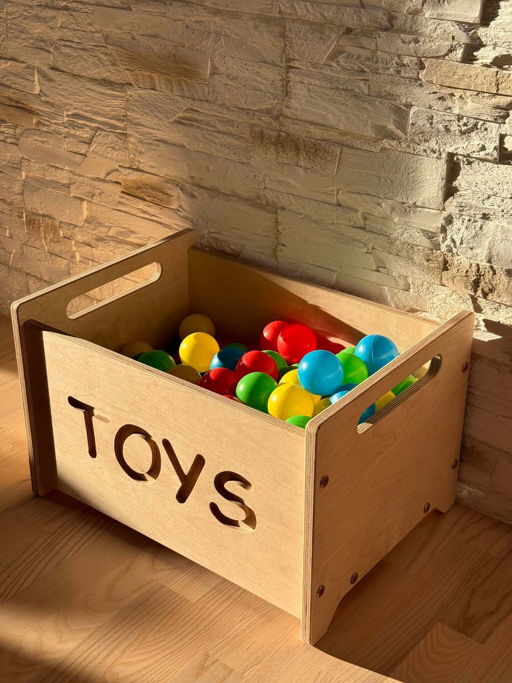 Montessori wooden toy box filled with colorful balls in a stylish playroom setting.