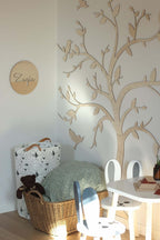 Wooden wall decoration tree birds enhancing a serene ambiance in children's playroom with stylish furniture.