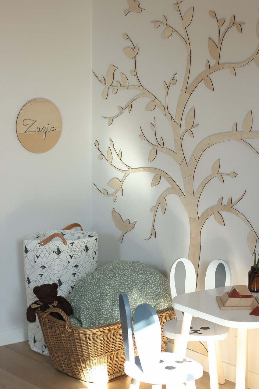 Wooden wall decoration tree birds enhancing a serene ambiance in children's playroom with stylish furniture.